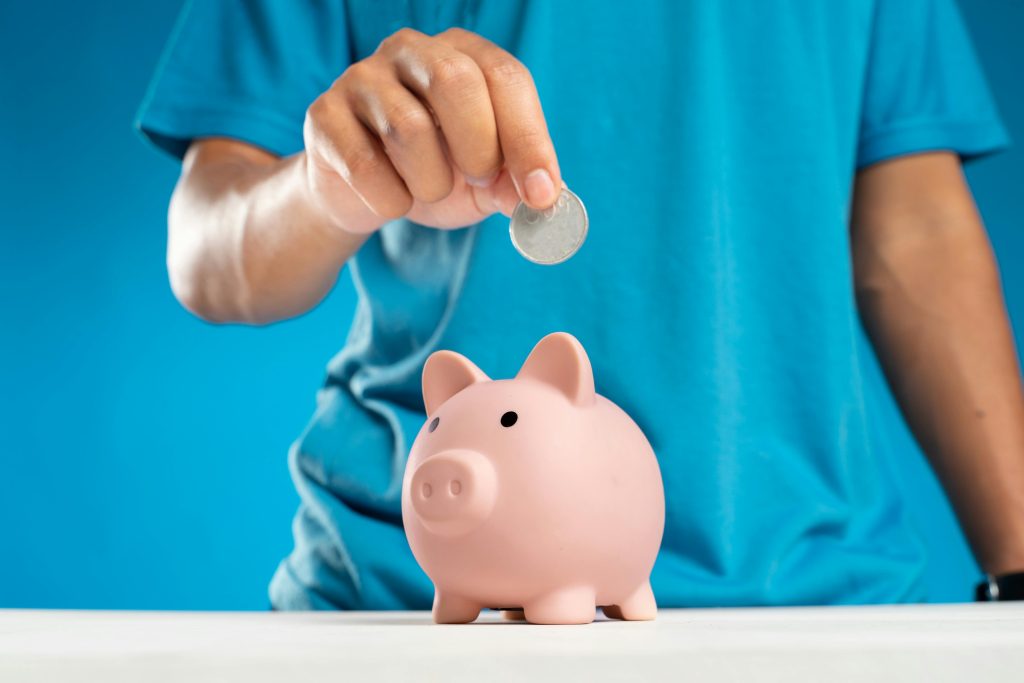 A person saving spare change into a piggy bank.